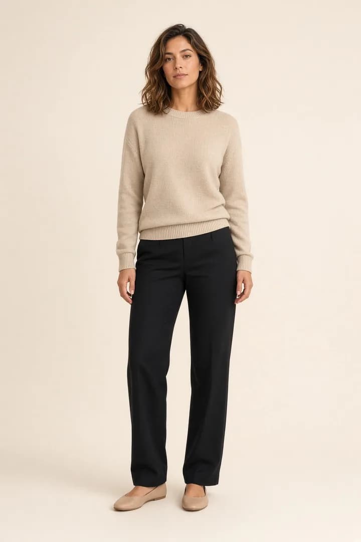Model standing in a beige sweater and black trousers
